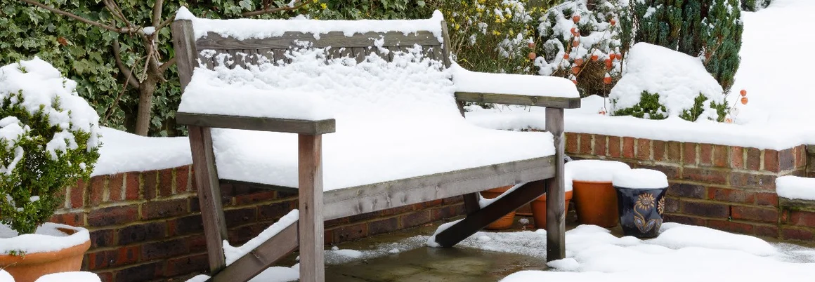 Gartenbank und Töpfe mit Schnee bedeckt